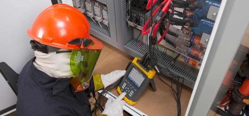 Técnico con equipo de protección midiendo un tablero eléctrico